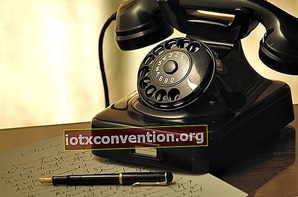 En gammal telefon som ligger på ett bord med en blyertspenna och ett brev