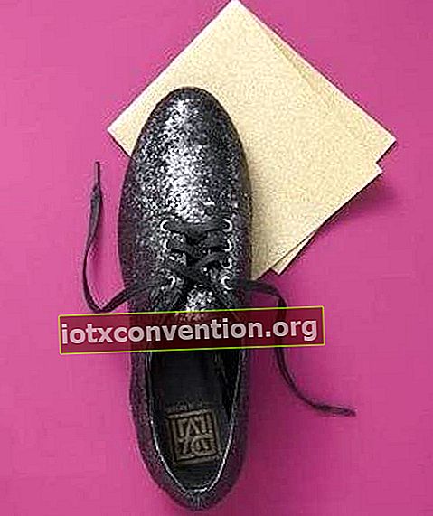 Ein schwarzer Schuh und Sandpapier, auf einem farbigen Hintergrund.