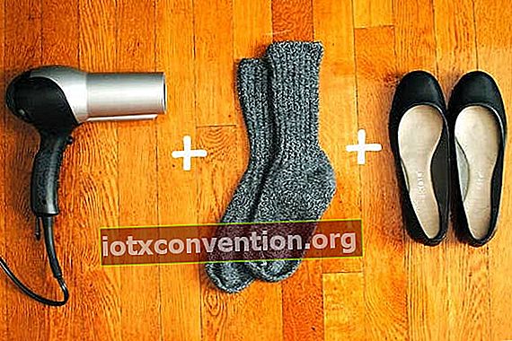 Dicke Socken, ein Haartrockner und schwarze Ballerinaschuhe auf Holzboden.