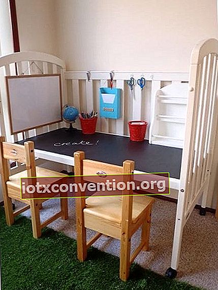 Tempat tidur bayi putih diubah menjadi meja dengan papan tulis