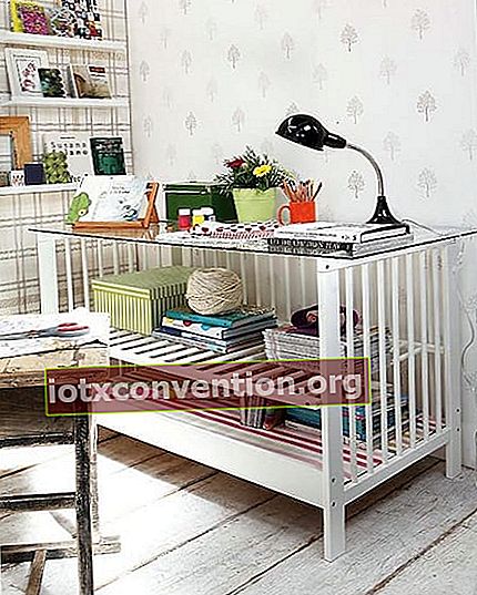 Tempat tidur bayi berwarna putih yang disulap menjadi meja atau meja dewasa