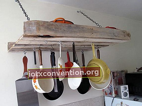 Töpfe und Pfannen hängen von einer Palette in einer Küche