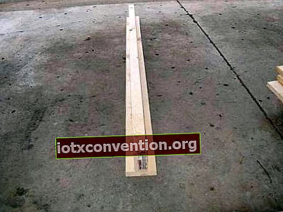 2 assi di legno assemblati a forma di T, su un pavimento di cemento.