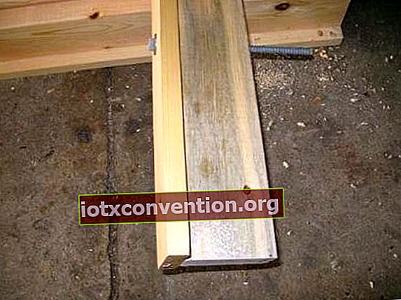 En fördröjningsskruv som korsar två träplankor monterade i T-form på ett betonggolv.