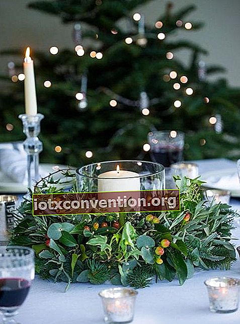 Kerzen umgeben von Kranz von Pflanzen auf dem Tisch