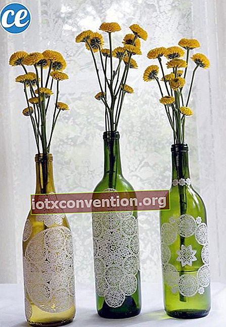 Tiga botol anggur dengan bunga kuning di dalamnya
