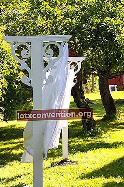 Eine altmodische weiß gestrichene Wäscheleine mit geschnitztem Holz in einem Garten zum Trocknen von Laken.