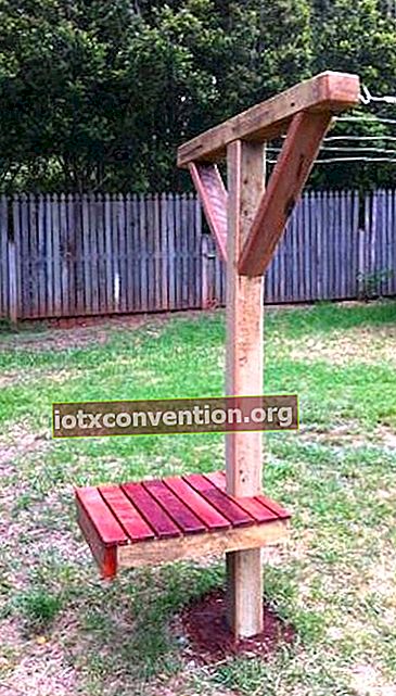 Un palo di legno stendibiancheria con una panchina in un giardino.