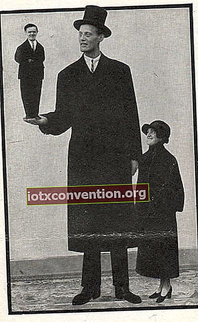 Uomo alto vestito di nero con un piccolo gentiluomo alla mano destra e una piccola signora dall'altra parte