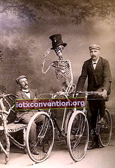 Skelett på en cykel bredvid två man med en sittande och den andra på en annan cykel