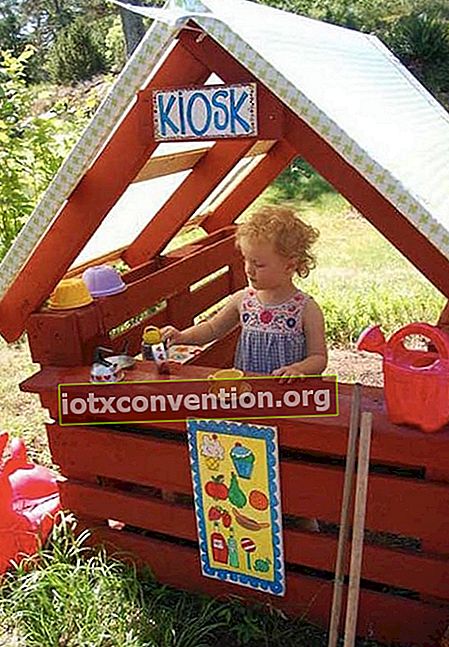 小さな女の子が遊んでいるパレットで作られた赤い食料品店