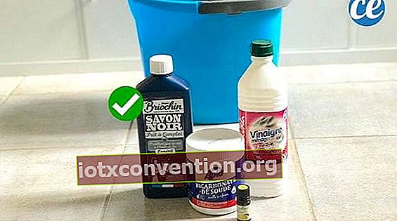 Sapone nero liquido, bicarbonato di sodio, aceto bianco, olio essenziale davanti a un sigillo blu per fare un detergente per pavimenti fatto in casa