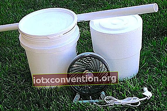 Un secchio da muratore, un secchio in polistirolo, un tubo in PVC e un ventilatore da tavolo per il condizionamento domestico.