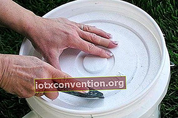 Hände, die eine Polystyrol-Eimerabdeckung ausschneiden, um eine Klimaanlage für zu Hause herzustellen.