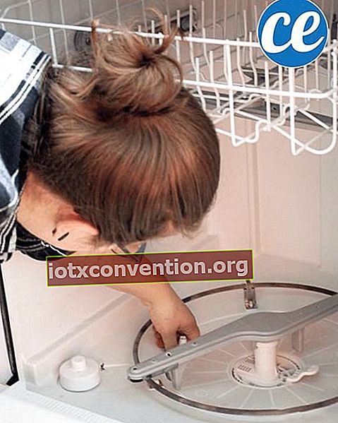 Seorang wanita membersihkan filter mesin cuci piringnya.