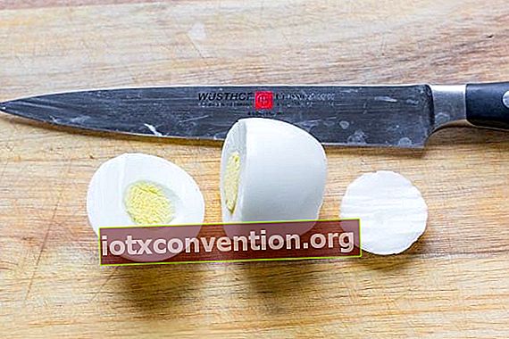 un uovo sodo viene tagliato con un coltello affilato 1/3 in alto e una fetta sottile in basso