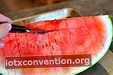En kniv som skär horisontella skivor i en vattenmelon.
