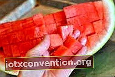En hand som rymmer en vattenmelon skuren i kuber.
